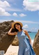 A woman in a blue polka dot dress and straw hat posing for a picture.