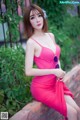 A woman in a pink dress sitting on a brick wall.