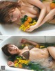 A woman laying in a bathtub with flowers in her hair.