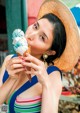 A woman in a straw hat eating an ice cream cone.