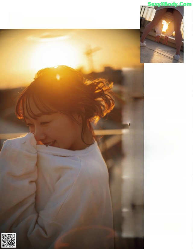 A woman in a white sweatshirt is looking at the sunset.