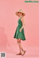 A woman in a green dress and straw hat posing for a picture.