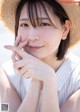 A woman wearing a straw hat and a white shirt.