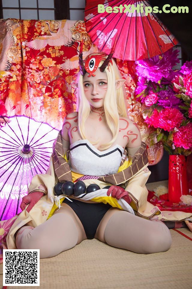 A woman in a kimono sitting on the floor with an umbrella.