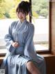 A woman in a blue hanbok sitting on a window sill.