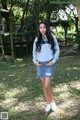 A woman in a gray sweatshirt and denim skirt posing for a picture.