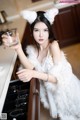 A woman in a white dress holding a glass of water.