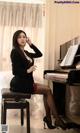 A woman sitting on a stool next to a piano.