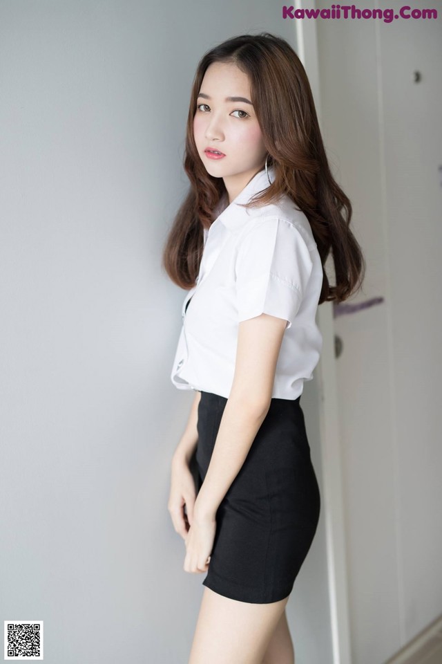 A woman in a white shirt and black skirt posing for a picture.
