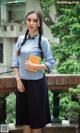 A woman in a blue shirt and black skirt holding a book.