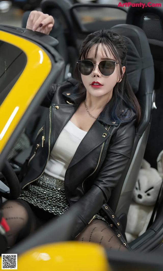 A woman sitting in the driver's seat of a yellow sports car.