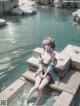 A woman sitting on a wooden dock in the water.